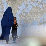 A burqa-clad woman walks with a girl along a street in Kabul on May 7, 2022