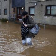 A woman wades through the flood waters near some houses in Brechin