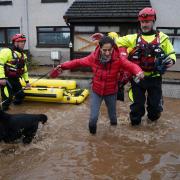 A member of the emergency services helps resident Laura Demontis from a house in Brechin