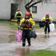 Members of the emergency services help local residents carry their possessions from homes in Brechin, Scotland