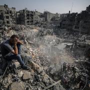 A man, sitting on debris, reacts as Palestinians conduct a search and rescue operation after the second bombardment of the Israeli army in the last 24 hours at Jabalia refugee camp in Gaza City