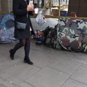 A woman walks past homeless people's tents