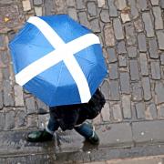 A member of the public with a Saltire umbrella walks along Victoria Street, Edinburgh