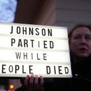 A woman protests after the arrival of former British Prime Minister Boris Johnson at the Covid Inquiry