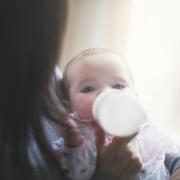 Mother feeding daughter formula from baby bottle