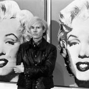 Andy Warhol, stands in front of his double portrait of the late Hollywood film star, Marilyn Monroe