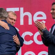Scottish Labour MP Michael Shanks embraces party leader Keir Starmer while MSP Anas Sarwar looks on