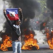 A demonstrator holds up an Haitian flag during protests demanding the resignation of Prime Minister Ariel Henry in Port-au-Prince, Haiti, Friday, March 1, 2024