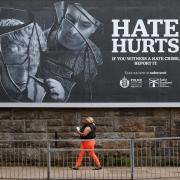 A member of the public walks past a hate crime billboard in Glasgow
