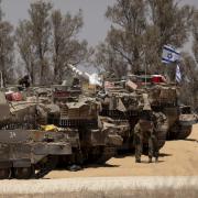 Israeli soldiers stand near tanks a long the border with the Gaza Strip on May 29, 2024