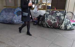 A woman walks past homeless people's tents
