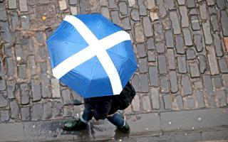 A member of the public with a Saltire umbrella walks along Victoria Street, Edinburgh