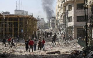 Palestinians walk through destruction in Gaza City on Friday