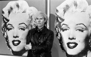 Andy Warhol, stands in front of his double portrait of the late Hollywood film star, Marilyn Monroe