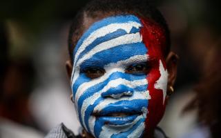 A Papuan student paints her face with the West Papua flag, the Morning Star during a rally in Jakarta, Indonesia