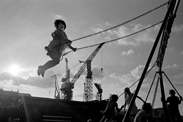 Nick Hedges’ photograph of girls playing on swings by the Govan shipyards in 1970